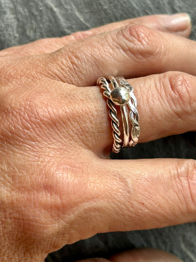close up of hand wearing silver braided ring, twisted rope ing and ball ring