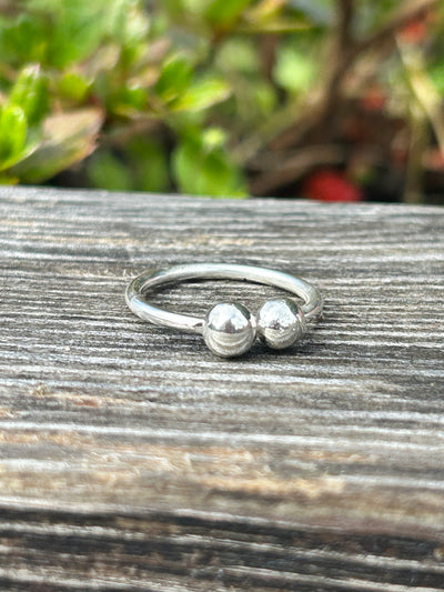 Silver ring featuring two balls on a wooden surface