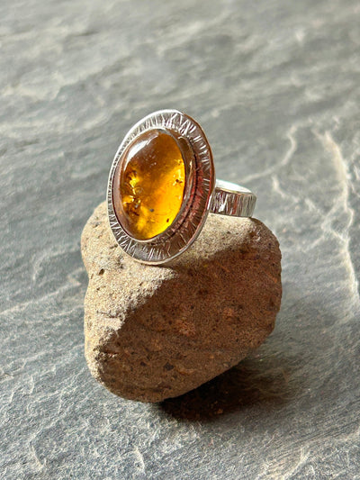 Silver ring with an amber gemstone on a stone surface
