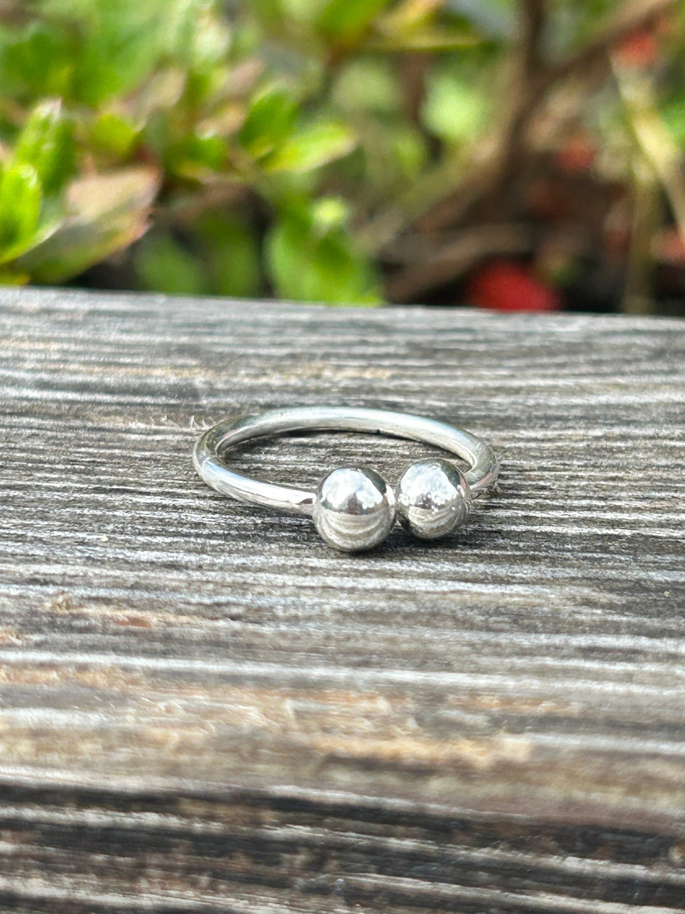 Silver ring featuring two balls on a wooden surface