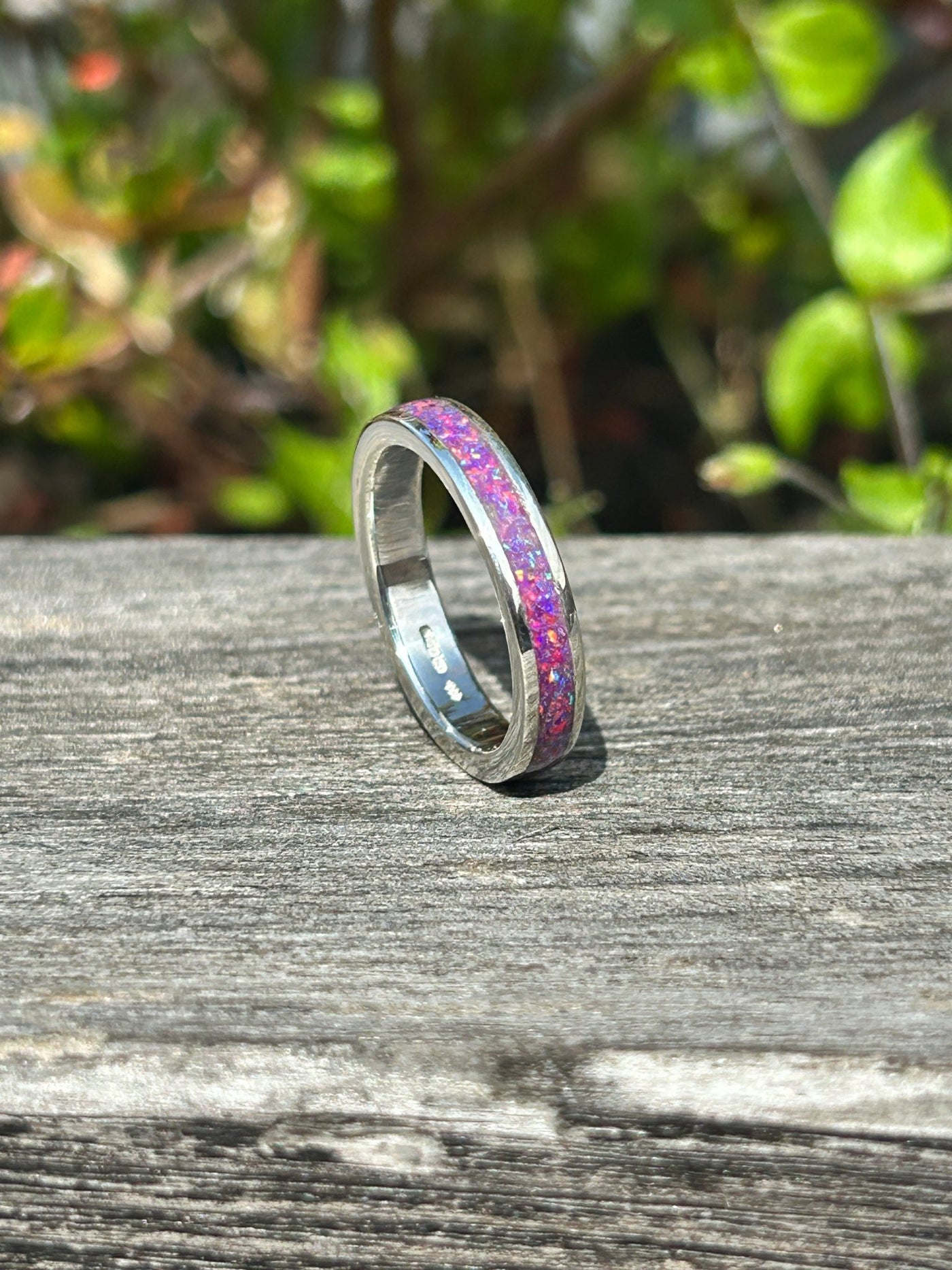 Silver opal inlay ring with sleepy lavender opal inlay set in it shown on a wooden surface
