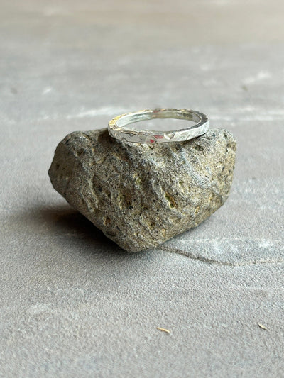 a rounded hammered silver stacking band shown on a stone