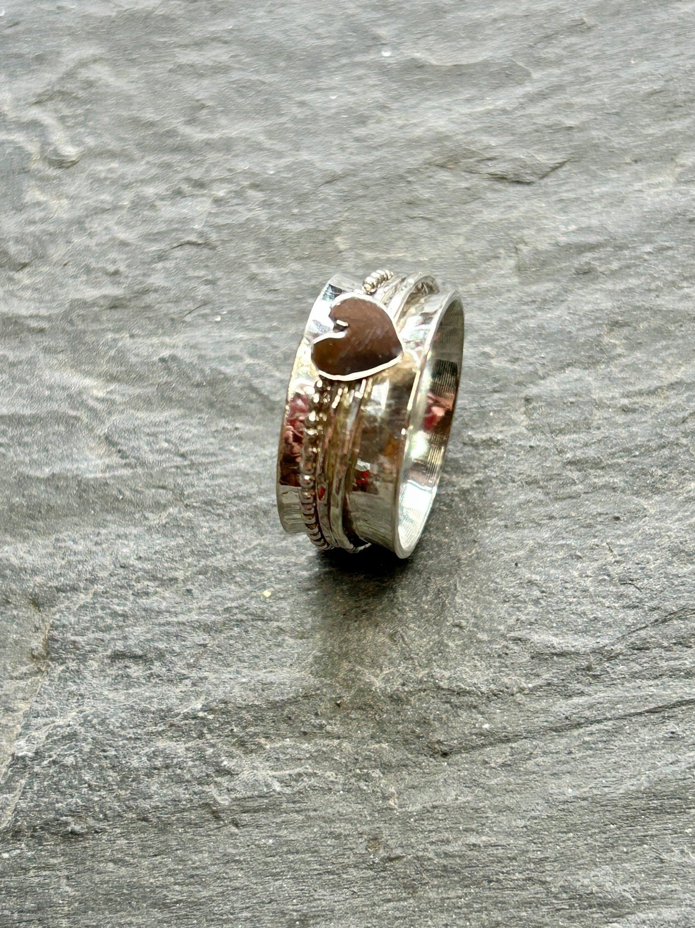 Sterling Silver Heart Spinner ring with three spinning bands on a slate background side on