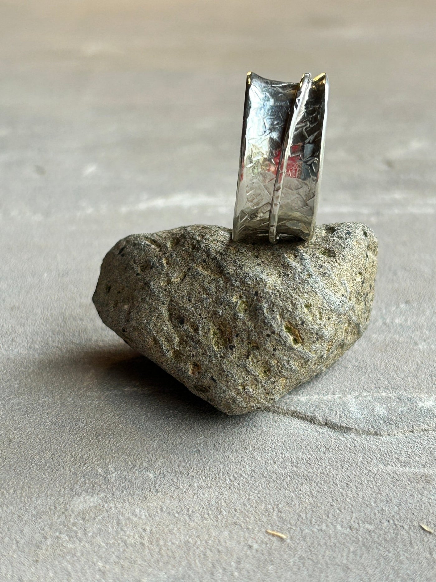 Sterling silver spinner ring with one silver outer spinning band shown on it's side on a stone