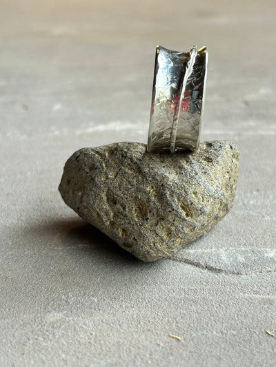 Sterling silver spinner ring with one silver outer spinning band shown on it's side on a stone