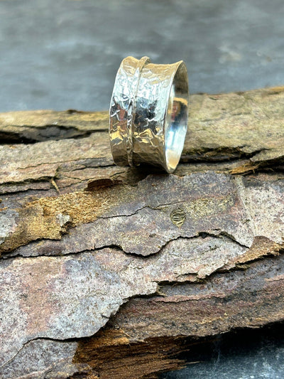 Wide Sterling silver spinner ring with one silver outer spinning band shown on a log