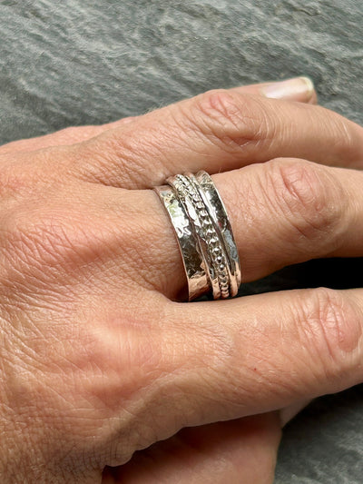 Silver spinner ring with three outer spinning bands shown on a hand